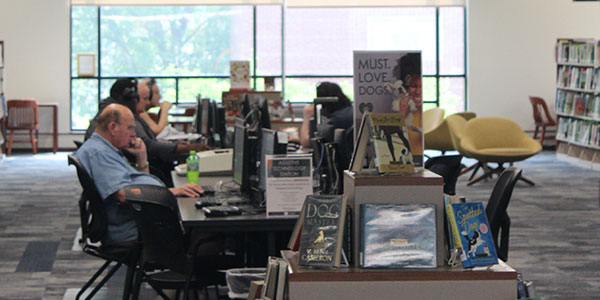 multiple people sitting at computers inside the library