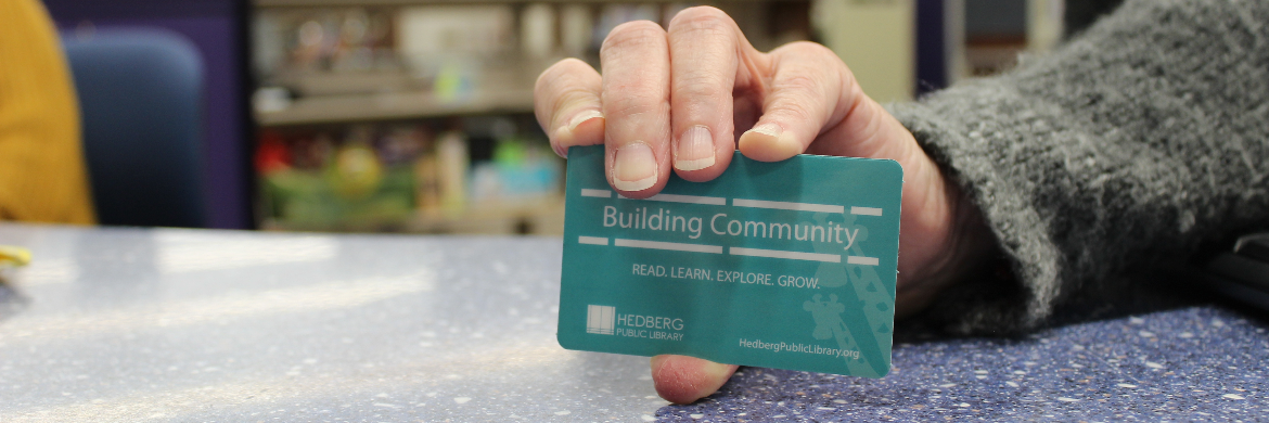 hand holding a blue library card