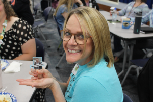 smiling blonde woman with glasses holding a sign that says welcome eric