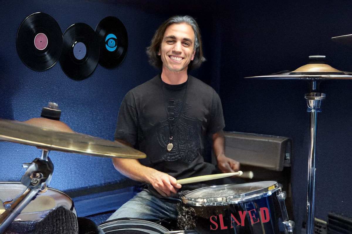 man playing the drums and smiling at camera