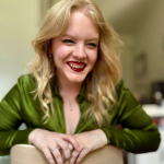 woman with blonde hair wearing a green shirt and smiling to the camera
