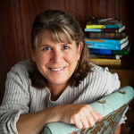 woman with dark blonde hair and bangs smiling at the camera