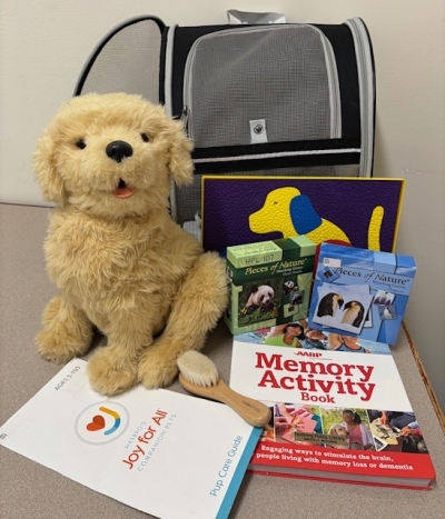 stuffed dog and books sitting in front of a dog carrier