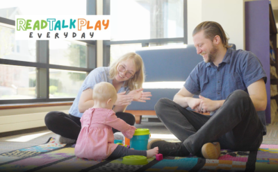 readtalkplayeveryday a mother and father sit with their infant 