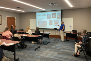 woman standing in front of screen leading a discussion in front of an audience