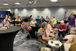 room full of people sitting at tables enjoying snacks