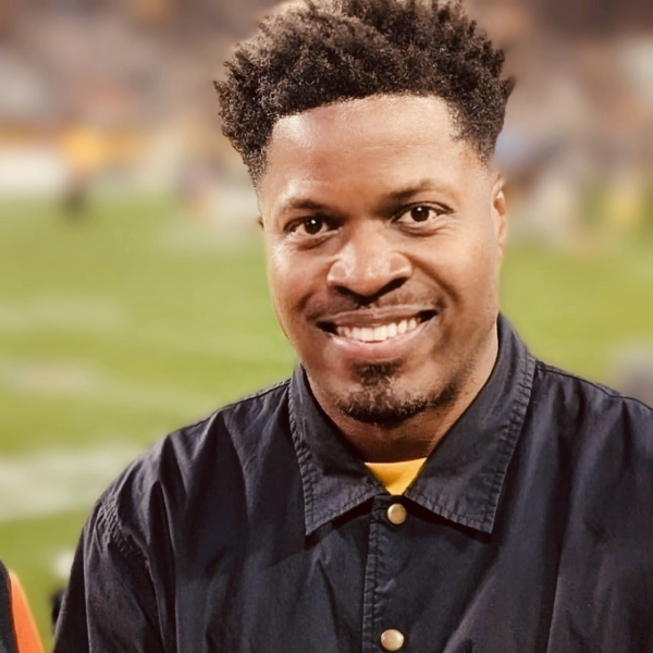 african american man wearing a black button up shirt smiling at the camera