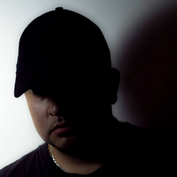 man wearing black baseball cap and black tshirt with his face half in shadow