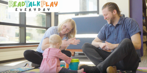 readtalkplayeveryday a mother and father sit with their infant 