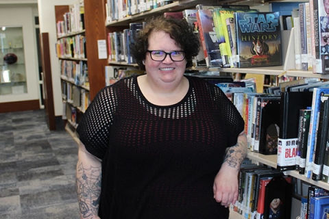 woman with short dark hair wearing glasses and a short sleeve black shirt