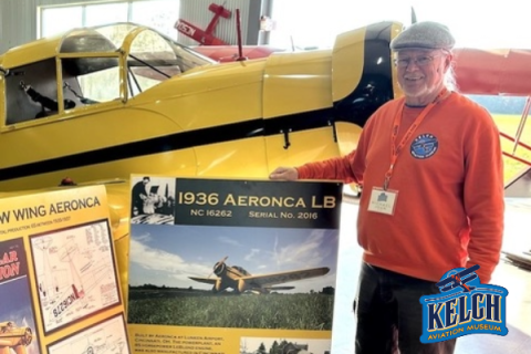 Middle aged man stands next to yellow prop plane 