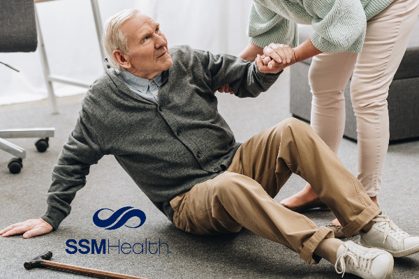 older man holding the hand of a helper to get off the ground