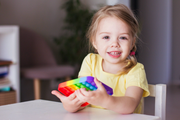 smiling toddler holding a colorful fidget
