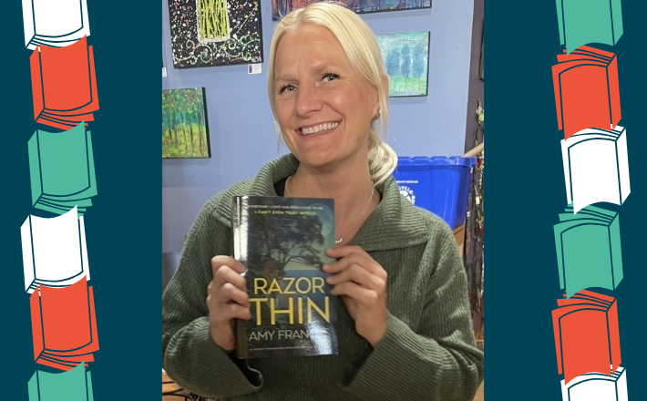 woman with blonde hair holding a book and smilling at the camera