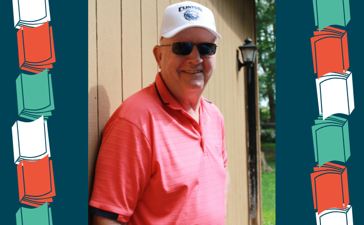 Man wearing pink shirt with white hat and sunglasses smiling at camera