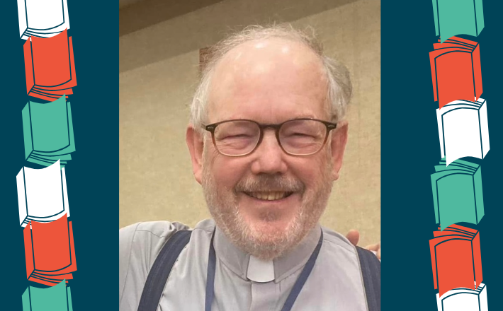 man with gray hair and beard wearing glasses and smiling at camera