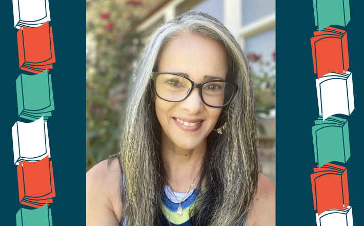 woman with long gray and black hair wearing glasses and smiling at camera