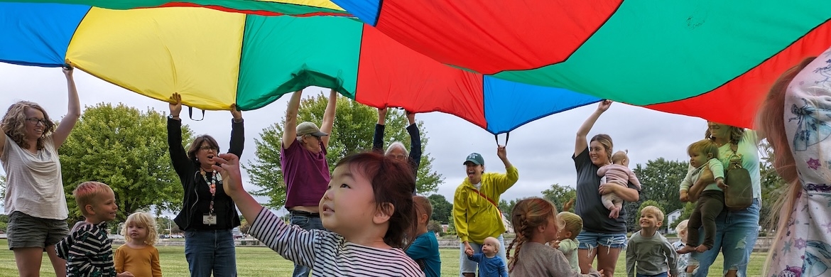 Children playing with colorful parachute outside